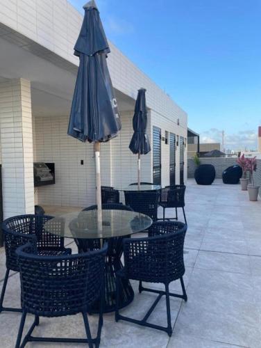 a table and chairs with an umbrella on a patio at Flat Beach Way caminho da praia in Cabedelo