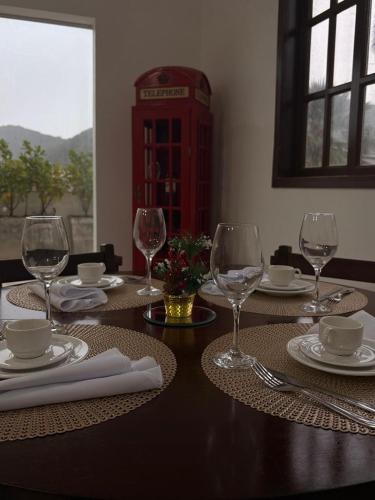 a table with wine glasses and a telephone booth at Pousada Três Marias - Guaiuba in Guarujá