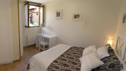 a bedroom with a bed and a desk and a window at Apartamento El Nial de Potes in Potes