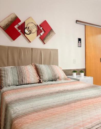 a bedroom with a bed with pictures on the wall at Pousada Três Marias - Guaiuba in Guarujá