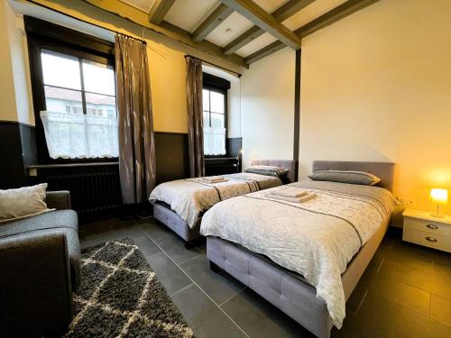 Pellinger-Hof في Pellingen: سريرين في غرفة بها نافذتين وأريكة