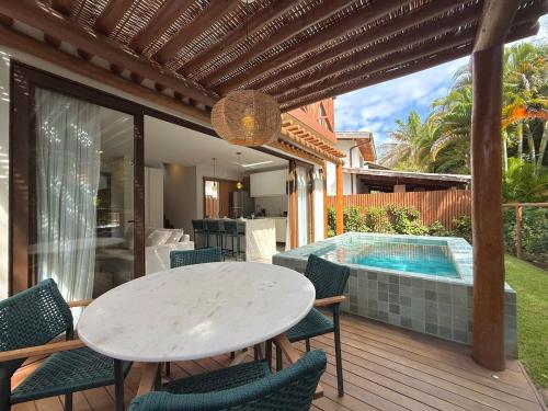 un patio con tavolo e sedie e una piscina di Villa Bougainville 01 - Natú a Mata de Sao Joao