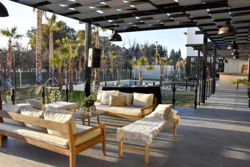 a patio with couches and tables and palm trees at Tótem Hotel & Spa in San Martín