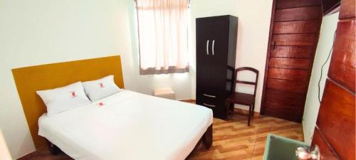 a bedroom with a white bed and a wooden door at Hostal los pulpos in Bombiso