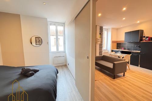 een slaapkamer met een bed en een bank en een keuken bij Le Cocon Rollin - Moderne & Confort in Roanne