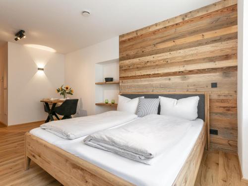Hopfgarten Alpin Living Top 4 في هوبفغراتن إم بريكسنتال: غرفة نوم بسرير ابيض كبير وبجدار خشبي