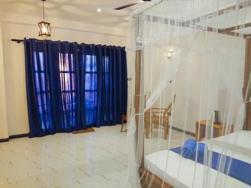 a living room with a large window with blue curtains at Mountain Relax Inn in Weligama