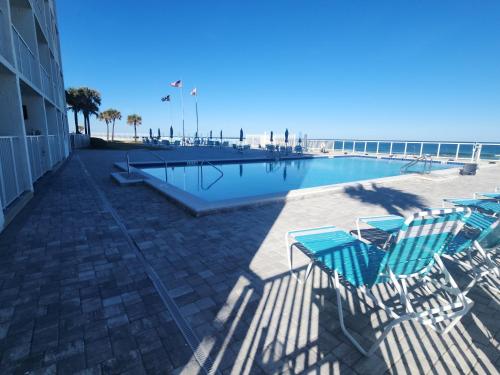 a swimming pool with lounge chairs and the beach at Purple Reign: A Chic, Romantic Oceanfront Getaway - Sleeps 4 in Daytona Beach