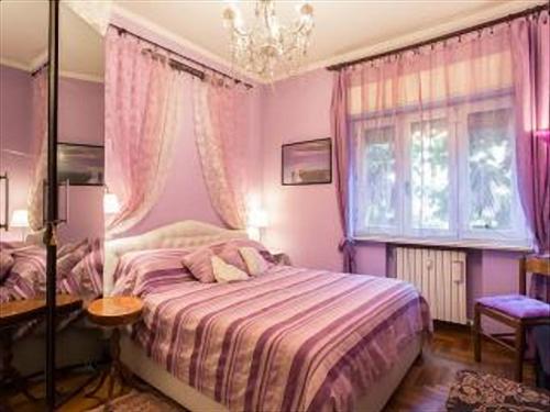 Habitación de color rosa con cama y ventana en Romantic & Artistic Apartment, en Milán