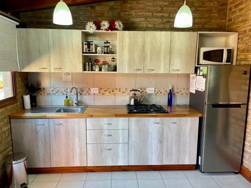 a kitchen with wooden cabinets and a stainless steel refrigerator at One Cabañas 2 in Los Antiguos