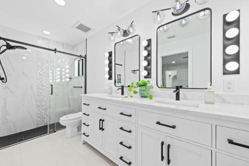 ポンパノビーチにあるWaterfront Villaの洗面台とトイレを備えた白いバスルーム
