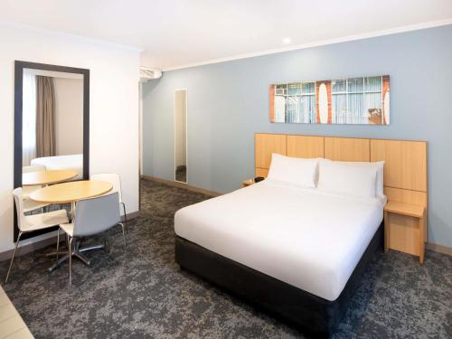 a hotel room with a bed and a table at Mercure Sydney Manly Warringah in Sydney