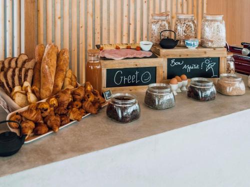 una mesa con varios tipos de pan y otros alimentos en ibis Styles La Rochelle Centre Gare, en La Rochelle