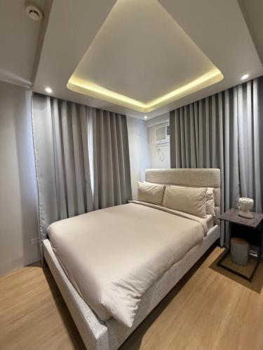 Schlafzimmer mit einem großen weißen Bett mit Vorhängen in der Unterkunft 1413 Home Suites Arezzo Place Davao in Davao City