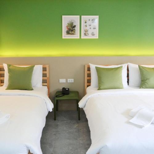 two beds in a room with a green wall at Chill Chill Hotel in Krabi