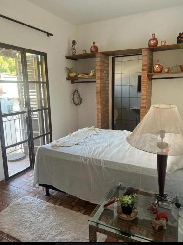 a bedroom with a bed and a glass table with a lamp at Áurea da Mata in Cuiabá