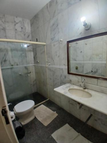 een badkamer met een toilet, een wastafel en een spiegel bij Áurea da Mata in Cuiabá