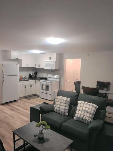 a living room with a couch and a kitchen at Private One Bedroom Basement Apartment with Separate Entrance in Dieppe