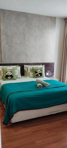 a bedroom with a bed with green sheets and panda pillows at NAT i-city smart house in Shah Alam