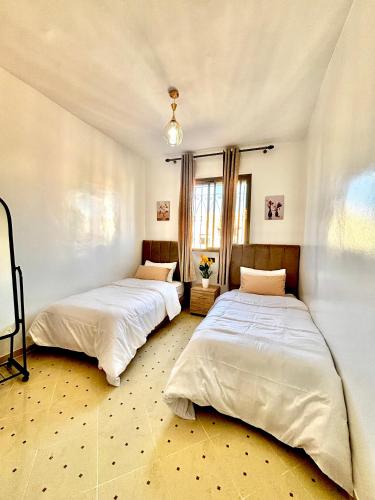 twee bedden in een kamer met witte lakens bij Zyarat Marrakech in Marrakesh