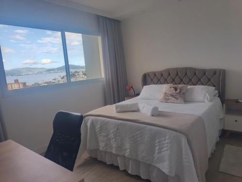 een slaapkamer met een bed met een groot raam bij Standard High Apartment in São José