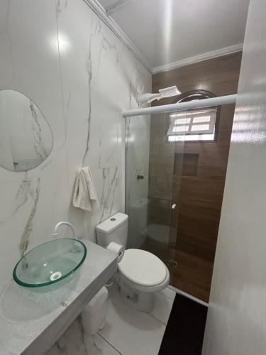 Un baño blanco con inodoro y lavabo de cristal. en Pousada do Moinho, en Cabo Frío