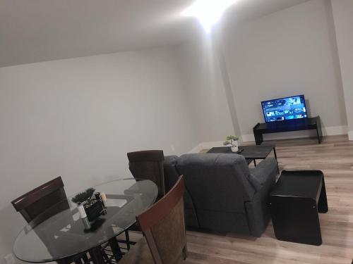 a living room with a couch and a table and a television at Private One Bedroom Basement Apartment with Separate Entrance in Dieppe