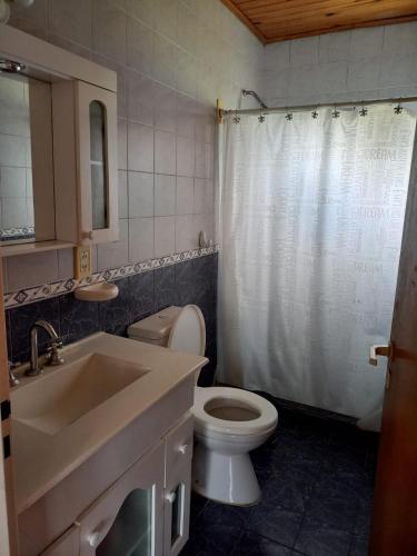 a bathroom with a white shower curtain and a toilet at Alquiler Villa Elisa in Villa Elisa