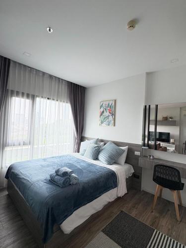 The Sriracha Perch في Ban Fang Daeng: غرفة نوم مع سرير وبطانية زرقاء ومكتب