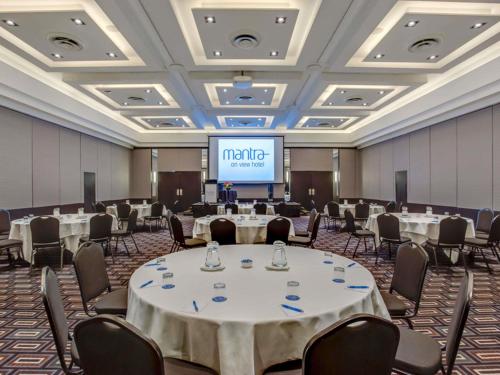 una sala de conferencias con mesas, sillas y una pantalla en Mantra on View, en Gold Coast