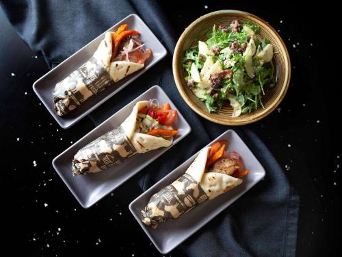 Una mesa con cuatro platos de comida y una ensalada. en Mantra MacArthur Hotel, en Canberra