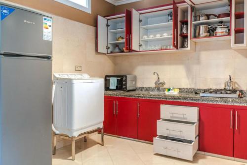 uma cozinha com armários vermelhos e um frigorífico branco em Appart hotel tanger em Dakhla