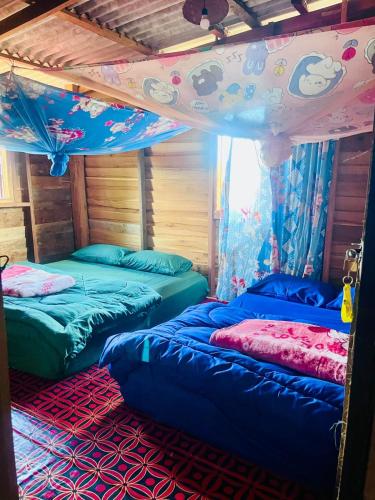 a room with three beds and a canopy at Mama Pap - Tad Lo in Ban Donkhagnoung