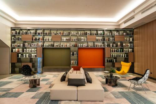 a library with a couch and chairs and bookshelves at lee hotel lat phrao in Bangkok