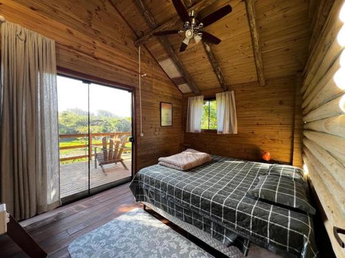 een slaapkamer met een bed en een groot raam bij Cabana do Lago- Morro da Borússia in Osório