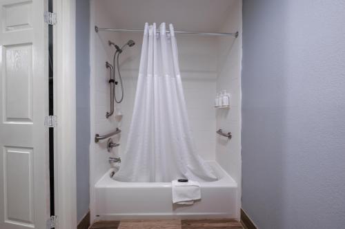 a white shower with a white shower curtain in a bathroom at Baymont by Wyndham Louisville Airport South in Louisville