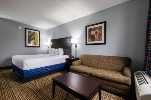 a hotel room with a bed and a couch at Baymont by Wyndham Louisville Airport South in Louisville