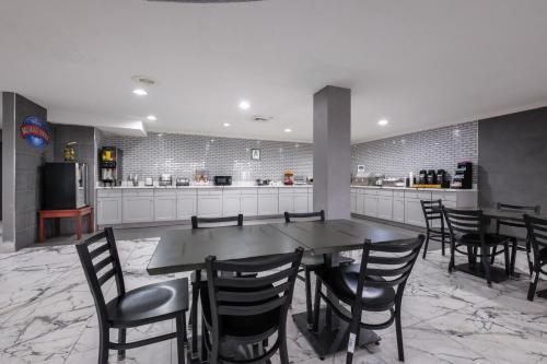 a dining room with a table and chairs and a kitchen at Baymont by Wyndham Louisville Airport South in Louisville