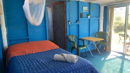 a bedroom with blue walls and a bed and a table at Polonesa in Cabo Polonio