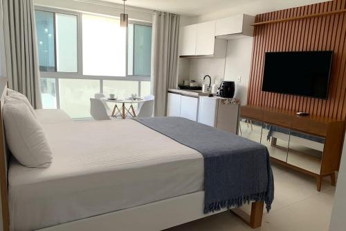 a bedroom with a large bed and a kitchen at Estúdio a 1 min do mar - Mila rooftop in Tamandaré
