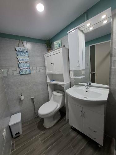 a bathroom with a white toilet and a sink at Hidden Palms Inn Garden Deluxe in San Juan