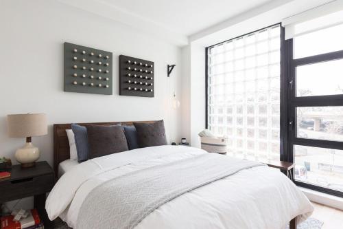 a white bedroom with a bed and a window at Stylish Williamsburg One Bedroom Condo Near Manhattan in Brooklyn
