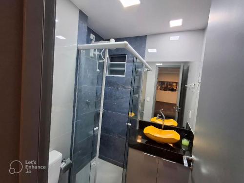 een badkamer met een douche en een gele wastafel bij Apto elegante no Catolé 301 in Campina Grande