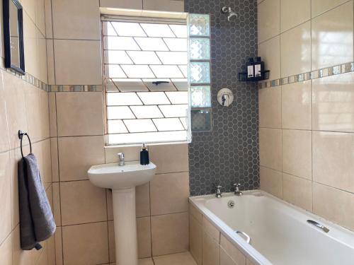 a bathroom with a sink and a bath tub at Unit 1 GatherPoint Sleeps 6 Self-Catering Group in Belhar, Cape Town in Belhar