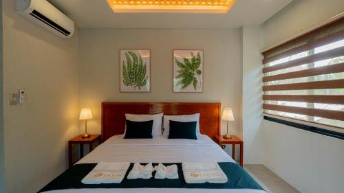 a bedroom with a bed with two lamps and a window at Dono Pool Villa & Spa in Dauis