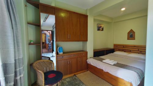 Tranquil Haven with shared kitchen access at greentara heritage home في باتان: غرفة نوم بسرير وكابينة وكرسي