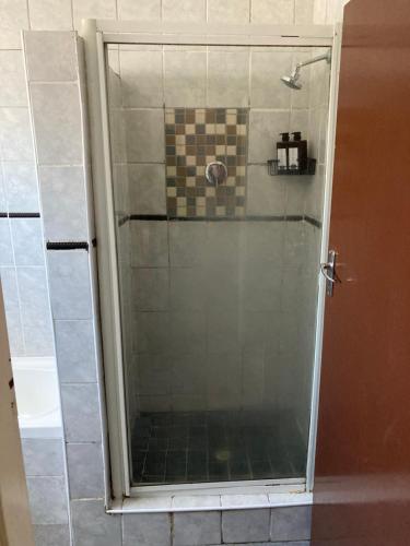 um chuveiro com porta de vidro em um banheiro em Unit 1, TraversHub Sleeps 6 Self-Catering Group Belhar, CT em Belhar