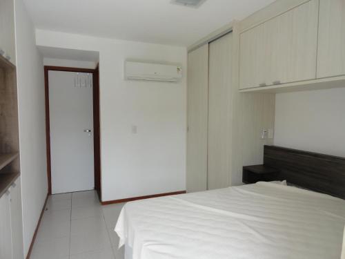 a white bedroom with a white bed and a door at Nannai residence Flat 202 in Porto De Galinhas