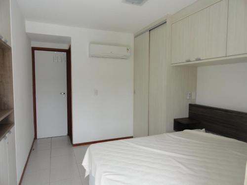 ein weißes Schlafzimmer mit einem weißen Bett und einer Tür in der Unterkunft Nannai residence Flat 202 in Porto De Galinhas