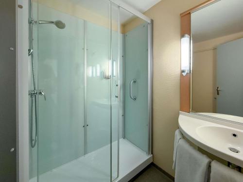 Un baño con ducha de cristal y lavabo. en ibis Rennes Beaulieu, en Cesson-Sévigné
